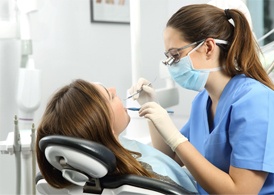 A dental hygienist removing plaque and tartar from a female patient’s smile