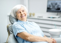 An older woman sitting in the dentist’s chair and smiling 