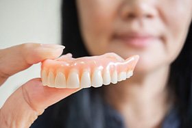 Woman holding dentures