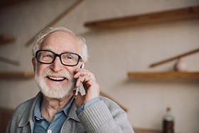 Man with dentures smiling and talking on the phone