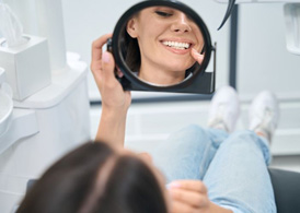 Dental patient admiring her smile after gum contouring