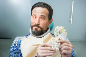 Man raising an eyebrow while looking at his dentures